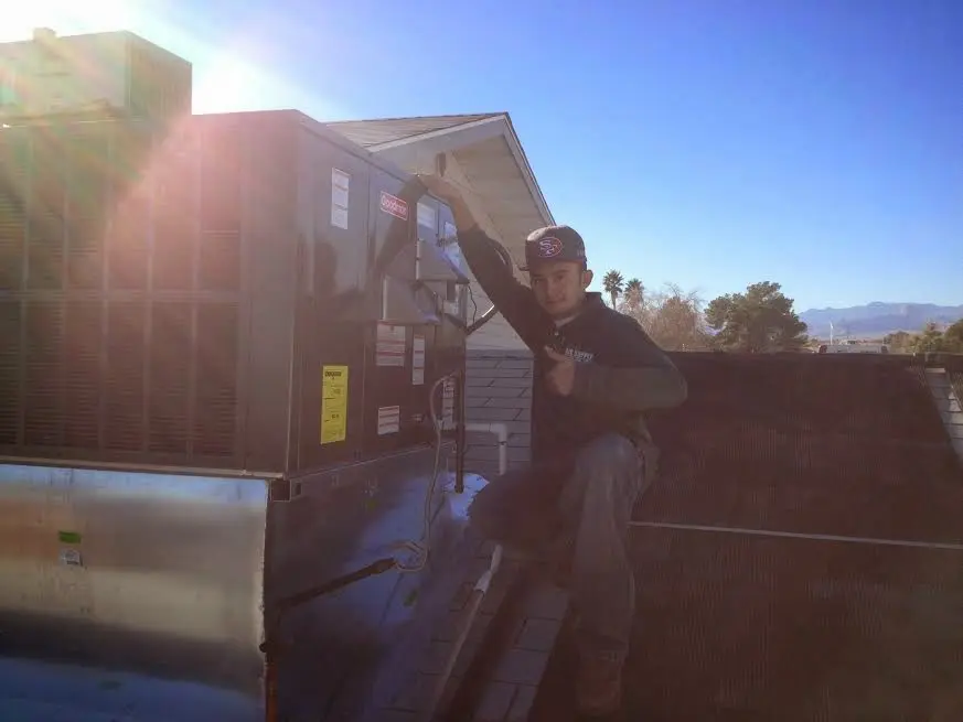 HVAC technician performing Air Duct Cleaning on a rooftop unit in Morton